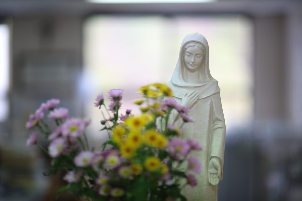 Statue of Mary in the background. Flowers in the foreground